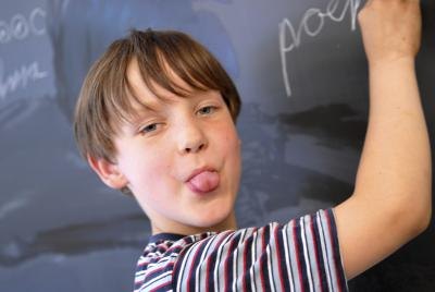 child sticking out tongue and writing on chalkboard child sticking out tongue and writing on chalkboard