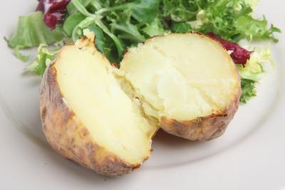 A plain baked potatoe with salad.