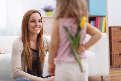 Daughter holding flower behind her back for mother Daughter holding flower behind her back for mother