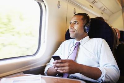 A business man listens to music on his smart phone while traveling on a train.