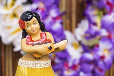 Close-up of a hula girl figurine in front of Hawaiian leis