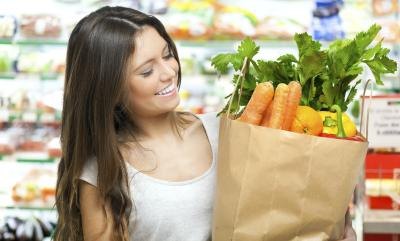 A woman is leaving the grocery store with healthy foods.