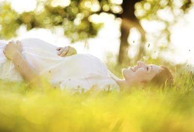 Pregnant woman smiling, lying in grass Pregnant woman smiling, lying in grass