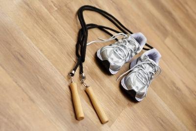 A close-up of cross training shoes and a jump rope on a wood floor. A close-up of cross training shoes and a jump rope on a wood floor.