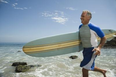 An older man run with a surfboard. An older man run with a surfboard.