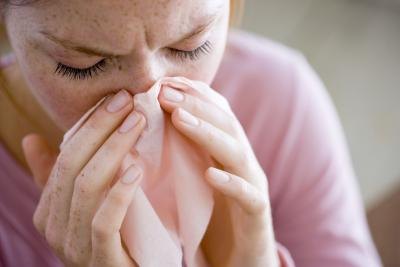 Woman holding tissue to nosebleed Woman holding tissue to nosebleed