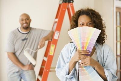 Woman holding paint swatches in front of her husband Woman holding paint swatches in front of her husband