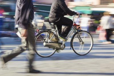 A person riding a bicycle and people walking in the street. A person riding a bicycle and people walking in the street.