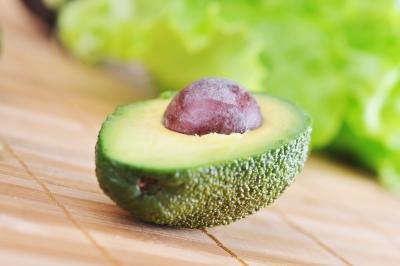 A halved ripe avocado on bamboo wood. A halved ripe avocado on bamboo wood.