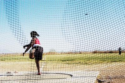 A discus thrower practices in a field. A discus thrower practices in a field.