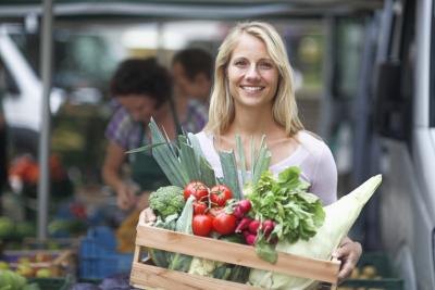 Smiling young woman holding crate filled with vegetables. Smiling young woman holding crate filled with vegetables.