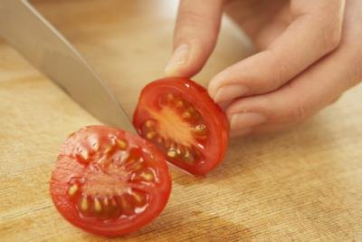 Close-up of tomato being sliced on cutting board. Close-up of tomato being sliced on cutting board.
