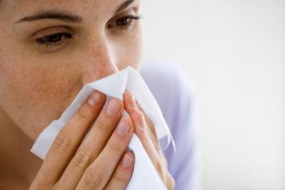 Woman coughing into tissue Woman coughing into tissue