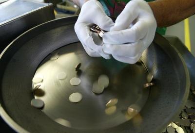 Blank nickel coins being added to machine Blank nickel coins being added to machine