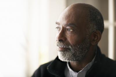 An older man stands near a window. An older man stands near a window.