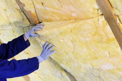 Man installing fiberglass insulation Man installing fiberglass insulation