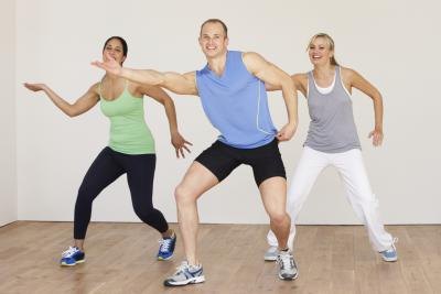 Three people doing zumba in a gym studio. Three people doing zumba in a gym studio.