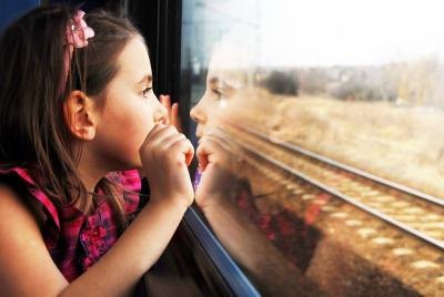 Young girl looking out train window. Young girl looking out train window.