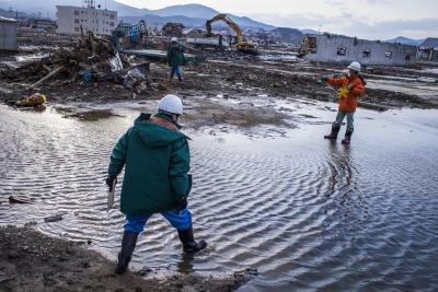 Two experts walk in the water at a site destroyed by an earthquake. Two experts walk in the water at a site destroyed by an earthquake.