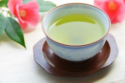 A cup of hot green tea on a table with cut flowers. A cup of hot green tea on a table with cut flowers.