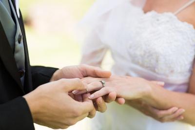 A close-up of a groom placing a wedding ring on a bride's finger. A close-up of a groom placing a wedding ring on a bride's finger.