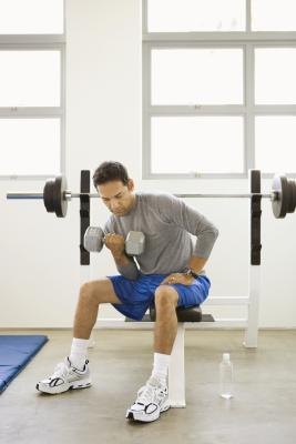 Seated dumbbell curls isolate the biceps muscles during each rep. Seated dumbbell curls isolate the biceps muscles during each rep.
