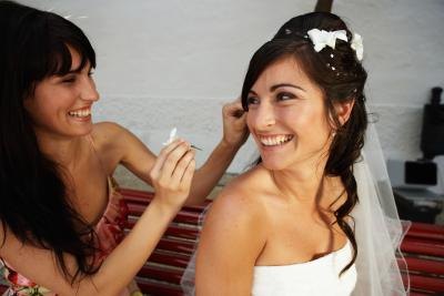A mistress of ceremonies puts a flower into a bride's hair. A mistress of ceremonies puts a flower into a bride's hair.