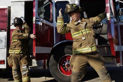 Two female firefighters exit a fire truck. Two female firefighters exit a fire truck.