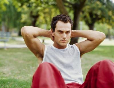 A man does sit ups in an outdoor park. A man does sit ups in an outdoor park.
