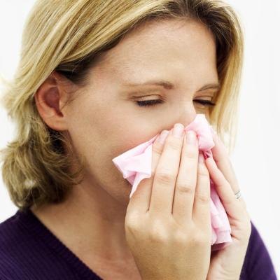 A woman blows her nose with a tissue. A woman blows her nose with a tissue.