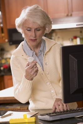 Woman looking at prescription and typing on computer Woman looking at prescription and typing on computer