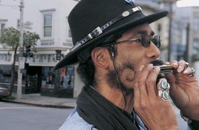 A man plays the harmonica while walking in the city. A man plays the harmonica while walking in the city.
