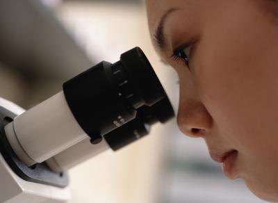 A young woman looks into a microscope. A young woman looks into a microscope.