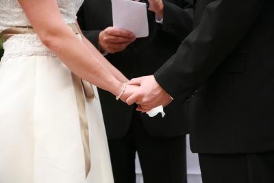 A bride and groom hold hands in front of a notary official. A bride and groom hold hands in front of a notary official.