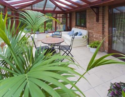 A sunroom with tile flooring, a patio table, living room furniture and plants. A sunroom with tile flooring, a patio table, living room furniture and plants.
