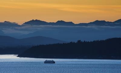 Ferry passes Bainbridge Island with Olympic Mountains in the background Ferry passes Bainbridge Island with Olympic Mountains in the background
