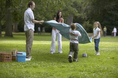 A family spreading out a picnic blanket in the grass