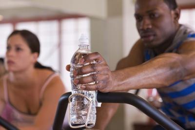 Man reaching for bottled water on exercise bike