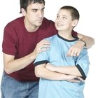 Father's hand on son's (7-9) shoulder, boy holding trophy, portrait