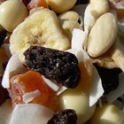 Mixed fruit, nuts and granola in a white bowl on wood table