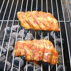 Man's hands dipping piece of roasted pork to ketchup