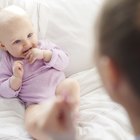 a young caucasian mother lies in the bed alongside her newborn baby