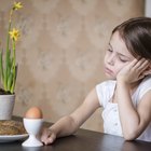 a young man feeding his daughter (1-3) on the table