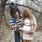 Pregnant woman sitting on mat in touching her belly