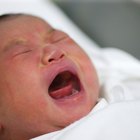 Newborn baby dressed in white laying on her back