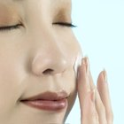 Close-up of a woman's hand applying lotion to her shoulder