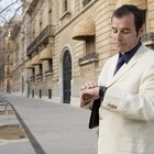 Mid adult man standing at street, looking at watch