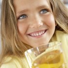 Young woman wearing pyjamas holding glass of juice, smiling, portrait