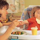 Baby girl (18-24 months) in high chair, spaghetti hanging over tray