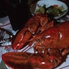 Grilled lobster tails on a plate wit asparagus and lemon wedges